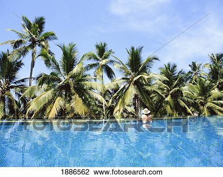 Stock Image - Woman In Infinity Pool And Palm Trees. Fotosearch