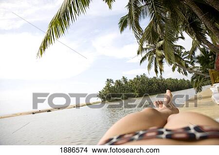 Picture - Woman In Patterned Bikini Sunbathing By Ocean. Fotosearch