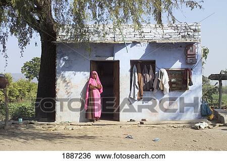 Stock Photograph - Woman In Pink Sari Standing In Doorway Of Her Village House. Fotosearch