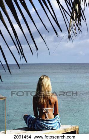Picture - Woman In Sarong Sitting On Sundeck Over Looking Sea At North Island Resort, North Island Seychelles.. Fotosearch