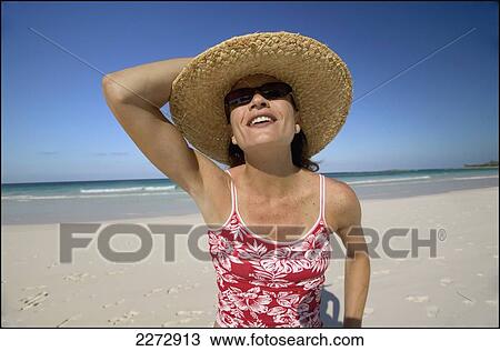Stock Image - Woman in sunglasses and sun hat on a beach; bahamas. Fotosearch