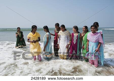 Woman in their saris standing in the surf at the water's edge; Gokarna, Karnataka, India View Large Photo Image Stock Photo - Woman in their saris standing in the surf at the water's edge; Gokarna, Karnataka, India. Fotosearch