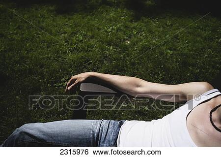 Stock Photograph - Woman In White Tank Top And Jeans Lounging On A Chair In The Back Yard; Otterburn Park Quebec Canada. Fotosearch