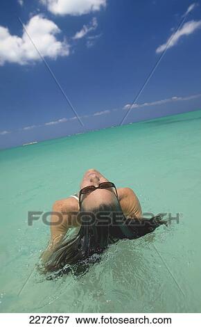 Stock Photo - Woman laying in water; bahamas. Fotosearch