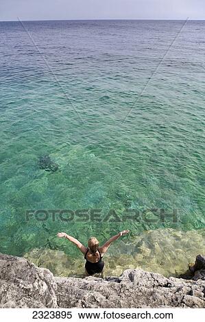 Woman lifting her arms to the sky on rocky shoreline in Bruce Peninsula National Park; Ontario, Canada View Large Photo Image Stock Photography - Woman lifting her arms to the sky on rocky shoreline in Bruce Peninsula National Park; Ontario, Canada. Fotosearch