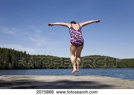Stock Photo - Woman Lifting Off A Cottage Dock To Dive Into A Lake In Algonquin Park; Ontario Canada. Fotosearch