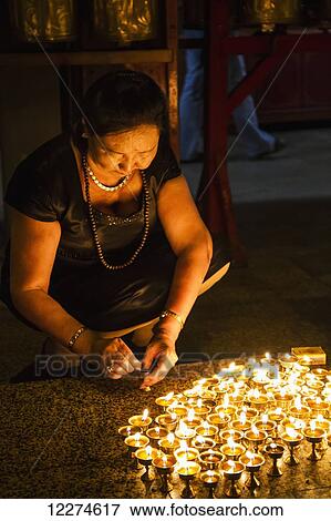 Stock Photo - Woman lighting butter lamps in the interior of Migjed Janraisig Temple at the Gandan Monastery (Gandantegchinlen Khiid), Ulaanbaatar (Ulan Bator), Mongolia. Fotosearch