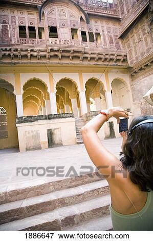 Stock Photo - Woman Listening To Headphones Photographing At Fort Mehrangarh. Fotosearch