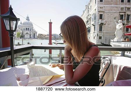 Stock Image - Woman Looking At Menu In Alfresco Cafe. Fotosearch