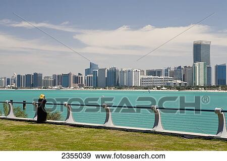 Stock Photo - Woman looking at the cityscape of Abu Dhabi; United Arab Emirates. Fotosearch
