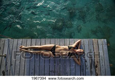 Picture - Woman Lounging On Resort Pier.. Fotosearch
