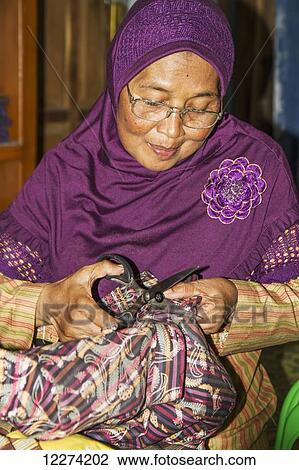Woman mending a garment at a lurik workshop in Cawas village, Klaten, Central Java, Indonesia View Large Photo Image Stock Image - Woman mending a garment at a lurik workshop in Cawas village, Klaten, Central Java, Indonesia. Fotosearch