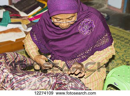 Stock Photo - Woman mending a garment at a lurik workshop in Cawas village, Klaten, Central Java, Indonesia. Fotosearch
