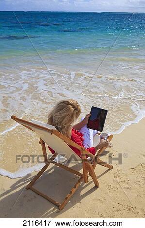 Stock Photo - Woman on beach uses electronic tablet.. Fotosearch