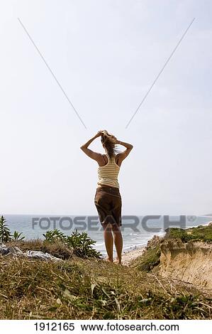 Stock Photography - Woman On Cliff Facing Ocean, Rear View, Ditch Plains, Montauk, Long Island, New York, Usa. Fotosearch