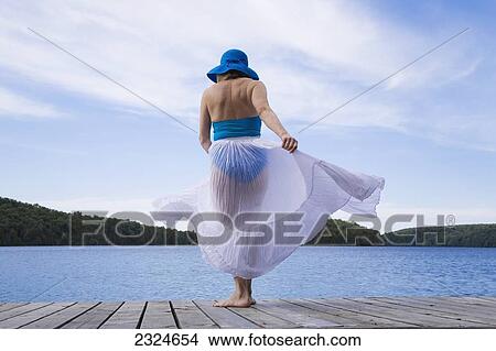 Picture - Woman On Cottage Dock With White Skirt Blowing In The Wind, Ontario, Canada. Fotosearch