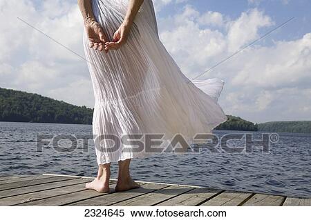 Stock Photography - Woman On Cottage Dock With White Skirt Blowing In The Wind, Ontario, Canada. Fotosearch