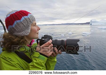 Stock Photograph - Woman On Midnight Cruise Around The Ilulissat Ice Fjord, One Of Unesco World Heritage Sites. Greenland.. Fotosearch
