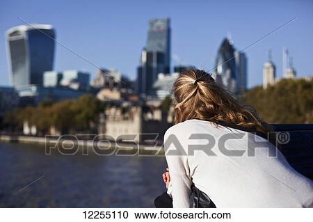 Woman on Tower Bridge overlooking the River Thames, the buildings of the City of London and the Tower of London; London, England View Large Photo Image Stock Image - Woman on Tower Bridge overlooking the River Thames, the buildings of the City of London and the Tower of London; London, England. Fotosearch