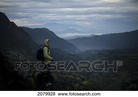 Woman Overlooking A Valley With Volcanos In The Background Early In The Morning; Cemoro Lawan Java Indonesia View Large Photo Image Stock Photo - Woman Overlooking A Valley With Volcanos In The Background Early In The Morning; Cemoro Lawan Java Indonesia. Fotosearch