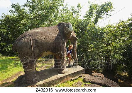 Woman peeking out from elephant statue at East Mebon Temple, built by Rajendravarman in the 10th Century; Cambodia View Large Photo Image Stock Photograph - Woman peeking out from elephant statue at East Mebon Temple, built by Rajendravarman in the 10th Century; Cambodia. Fotosearch