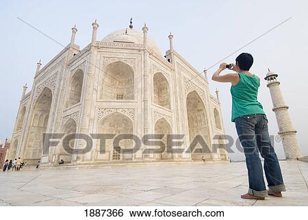 Stock Photograph - Woman Photographing The Taj Mahal At Dawn. Fotosearch