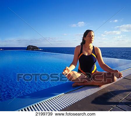 Stock Photo - Woman practising yoga beside a spa pool; Madeira, Portugal. Fotosearch