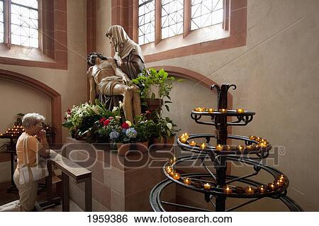 Stock Photograph - Woman Praying In Front A Of A Pieta Statue In The Cathedral Of Saint Bartholomew At Frankfurt Am Main, Germany. Fotosearch