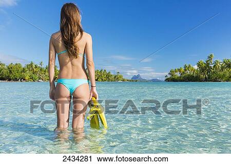 Stock Image - Woman ready to snorkel in aqua blue water; Tahaa, French Polynesia. Fotosearch