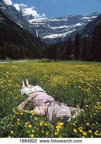 Stock Image - Woman Relaxing In Field Of Buttercups With The Cirque De Gavarnie In The Background. Fotosearch