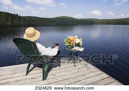Woman Relaxing On Cottage Dock With Wine And Flowers, Ontario, Canada View Large Photo Image Stock Photo - Woman Relaxing On Cottage Dock With Wine And Flowers, Ontario, Canada. Fotosearch