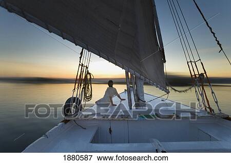 Stock Photo - Woman Relaxing On Deck Of Felucca At Dusk. Fotosearch