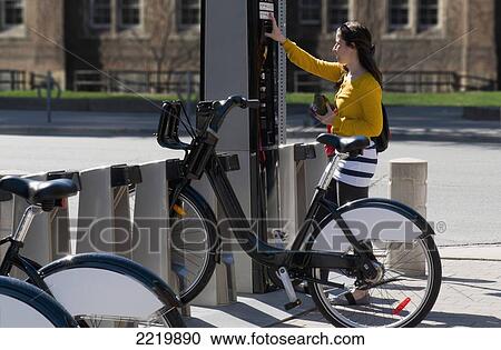 Stock Image - Woman Renting Bicycle And Paying Using A Card; Toronto Ontario Canada. Fotosearch