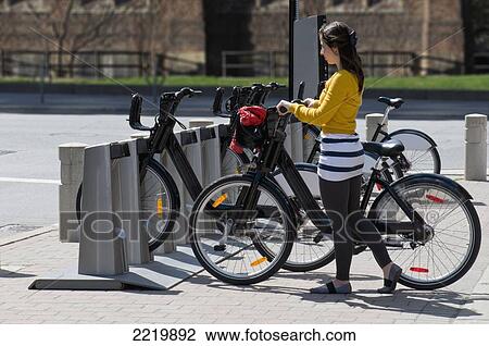 Woman Renting Bicycle And Removing It From Rack; Toronto Ontario Canada View Large Photo Image Stock Image - Woman Renting Bicycle And Removing It From Rack; Toronto Ontario Canada. Fotosearch