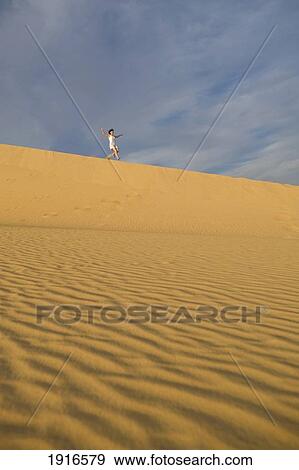 Stock Photo - Woman Running Down Sand Dunes. Fotosearch