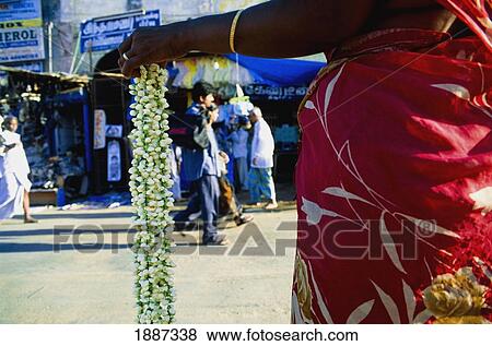 Stock Photo - Woman Selling Flower Garland On Street, Mid Section. Fotosearch