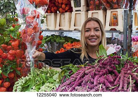 Stock Image - Woman selling flowers, Columbia Road Flower Market; London, England. Fotosearch