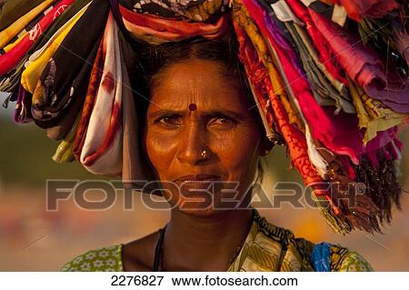 Stock Photo - Woman selling Indian cloth on the beach at dusk; Candolim, Goa, India. Fotosearch