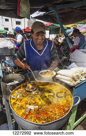Stock Image - Woman serving food at an eatery at the Thursday market, Guamote, Chimborazo, Ecuador. Fotosearch