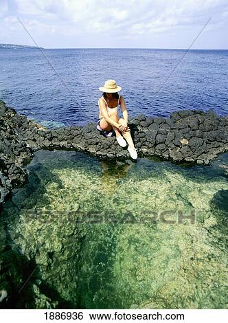 Stock Photograph - Woman Sitting By Rock Pools With Sea Behind. Fotosearch