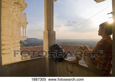 Stock Photography - Woman Sitting In Small Temple At Dusk. Fotosearch