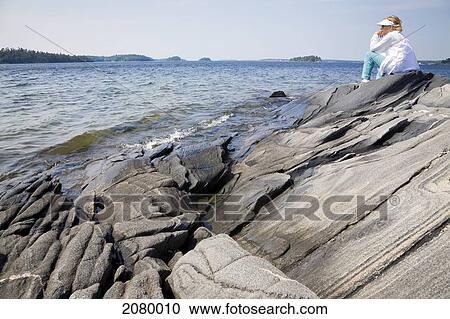 Woman Sitting On A Rocky Shoreline Overlooking Georgian Bay At Killbear Provincial Park; Ontario, Canada View Large Photo Image Stock Image - Woman Sitting On A Rocky Shoreline Overlooking Georgian Bay At Killbear Provincial Park; Ontario, Canada. Fotosearch
