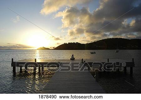 Stock Image - Woman Sitting On End Of Pier At Dusk. Fotosearch