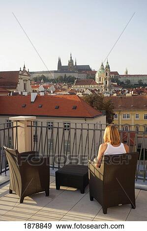 Stock Photo - Woman Sitting On Roof Terrace Overlooking Prague Castle. Fotosearch