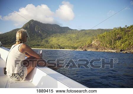 Stock Photography - Woman Sitting On Side Of Boat Heading Towards Island. Fotosearch