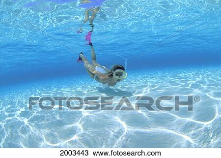Stock Image - Woman Snorkeler Near Surface Underwater In Clear Turquoise Water Sun Reflections On Sandy Bottom. Fotosearch
