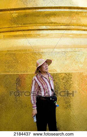 Stock Photo - Woman Standing In Front Of The Golden Phra Si Ratana Chedi At The Grand Palace. Bangkok, Thailand. Fotosearch