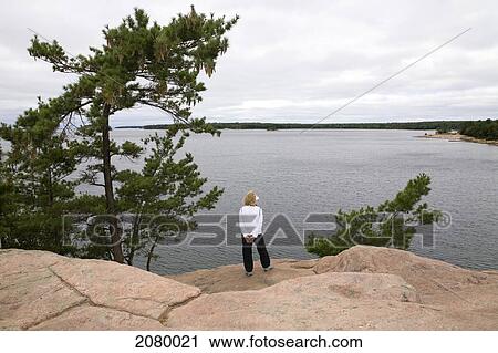 Woman Standing On A Rocky Ledge Overlooking Georgian Bay At Killbear Provincial Park; Ontario, Canada View Large Photo Image Stock Image - Woman Standing On A Rocky Ledge Overlooking Georgian Bay At Killbear Provincial Park; Ontario, Canada. Fotosearch