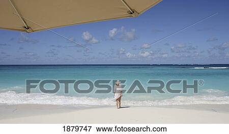 Woman Standing On A Tropical Beach With Umbrella In Foreground View Large Photo Image Stock Photo - Woman Standing On A Tropical Beach With Umbrella In Foreground. Fotosearch