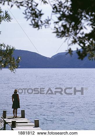 Stock Image - Woman Standing On Edge Of Pier. Fotosearch